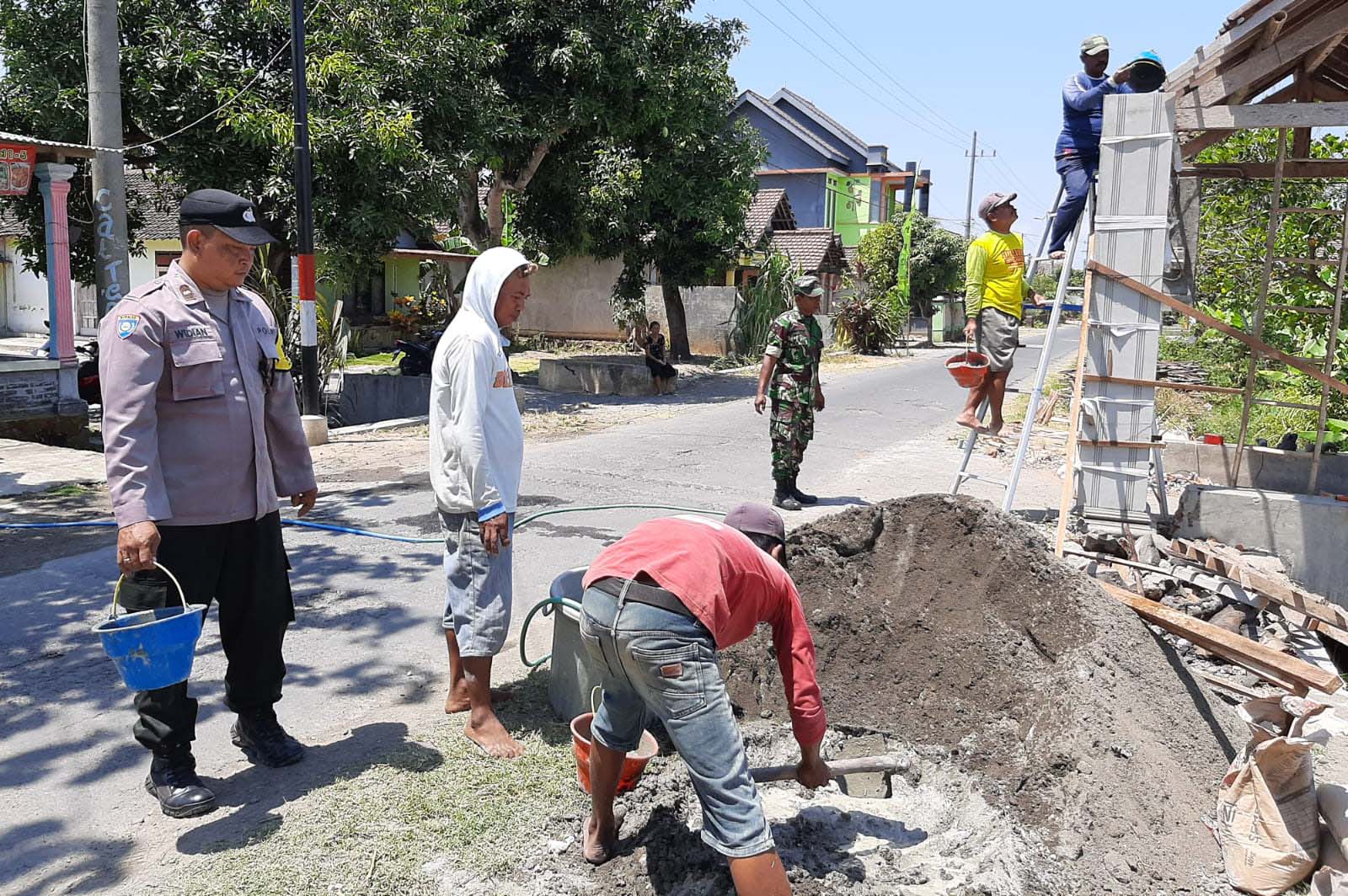 Dekatkan Diri Dengan Warga, Bhabinkamtibmas Wates Ikut Kerja Bhakti Bangun Gapura