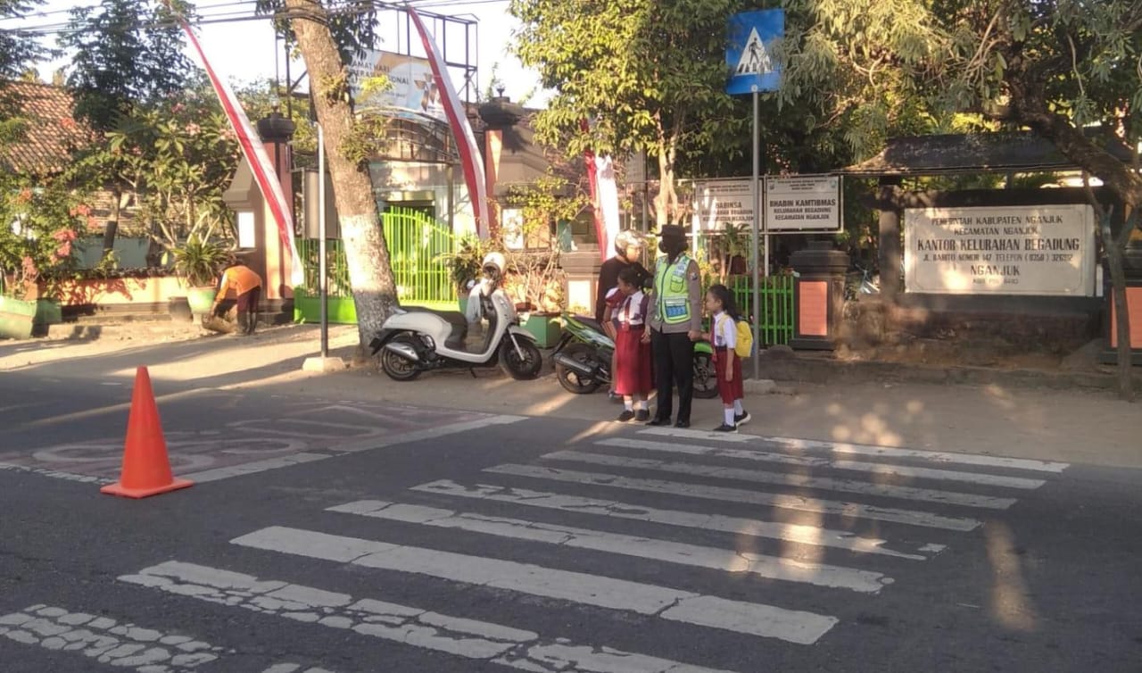 Giat Penampilan Pagi Anggota Polsek Nganjuk Kota Bantu Penyebrangan Warga Masyarakat yang Melaksanakan Aktivitas di Pagi Hari