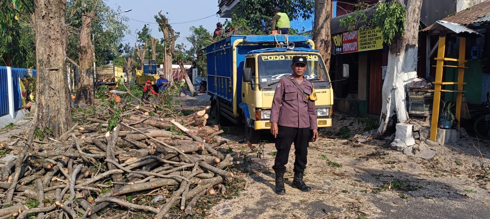 Demi Kelancaran Proses Penebangan Pohon Bhabinkamtibmas Polsek Nganjuk Kota Berikan Pengamanan dan Pengaturan Lalu Lintas